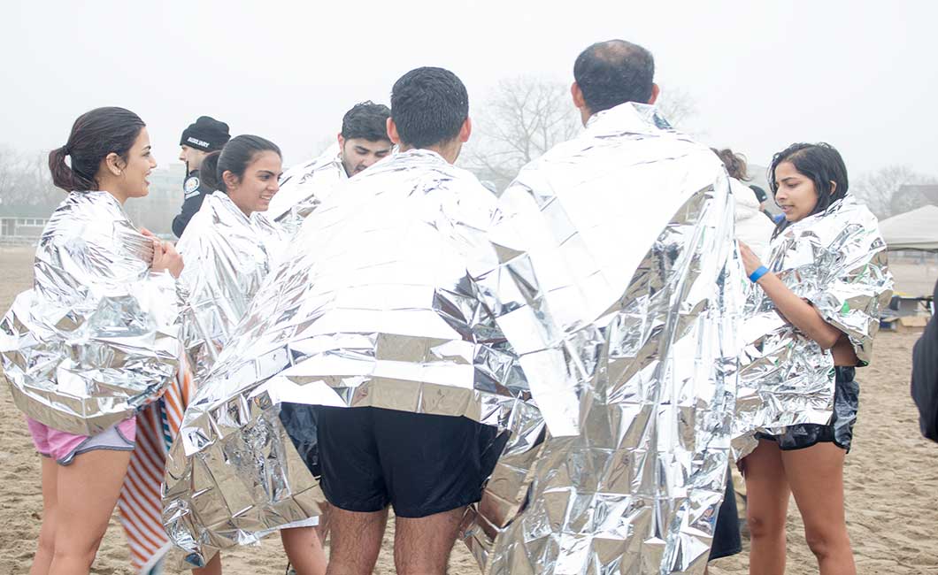 Plungers huddle around and keep warm with an aluminum foil blankets