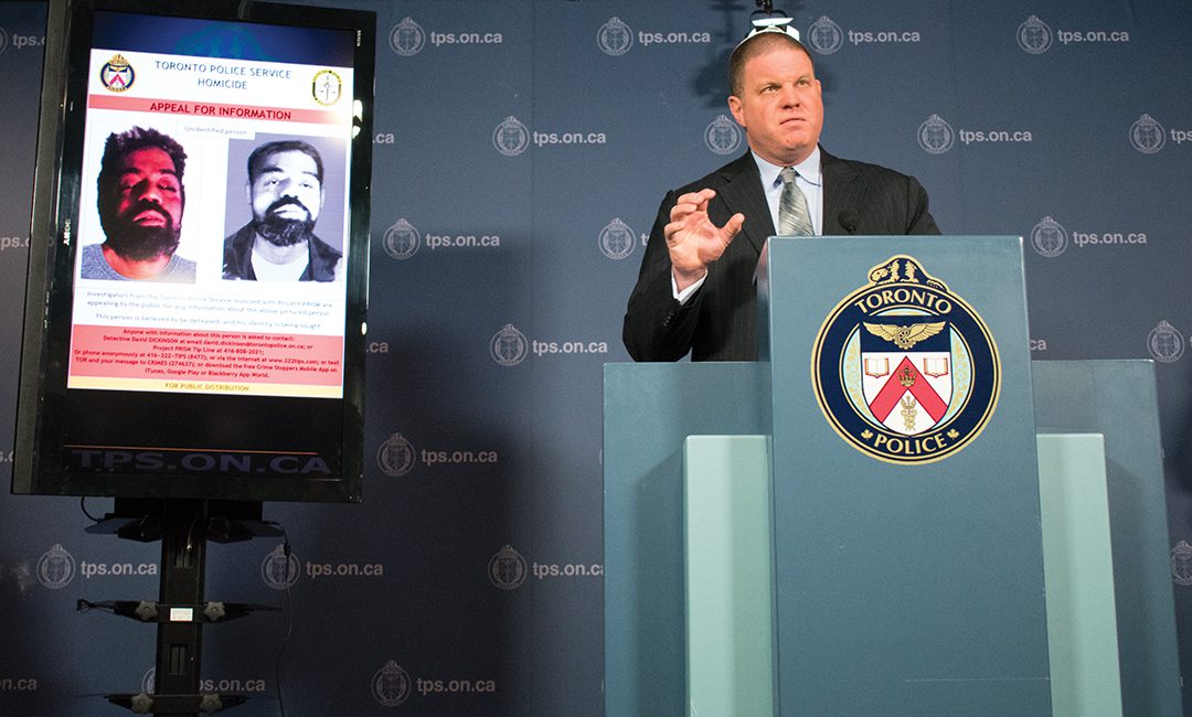 Det.-Sgt. Hank Idsinga addressing media questions beside an image and sketch of the unidentified man.