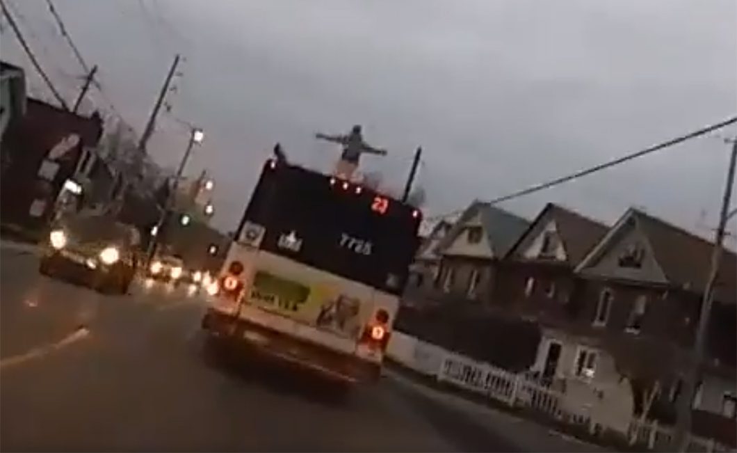 A video still of a man standing on a moving TTC bus.