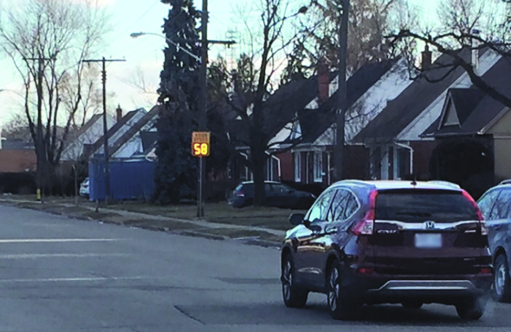 Car driving past speeding display sign.