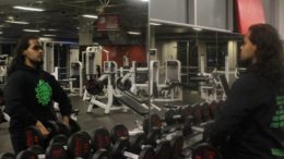 Person lifting weights at the gym in front of mirror.