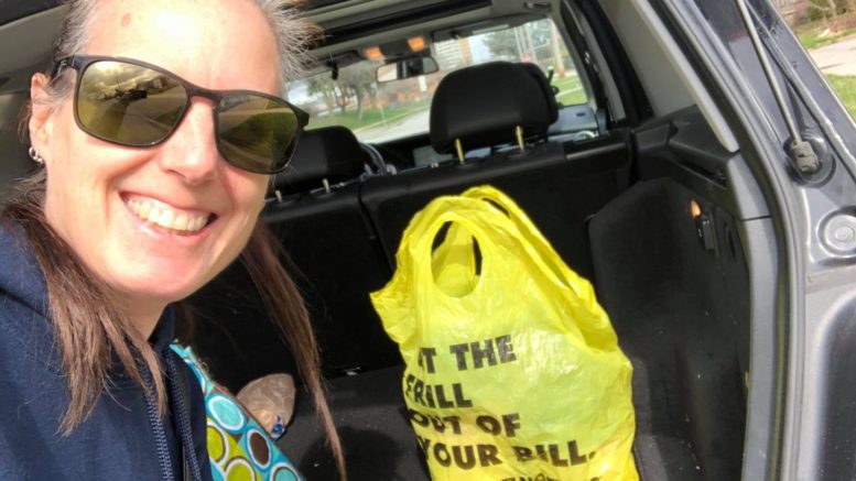 A Good Neighbour Project volunteer poses with a grocery bag in the trunk of her car