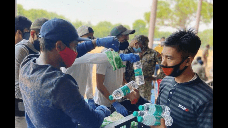 Bangalore Student Community volunteers distribute water bottles to migrant labourers stranded at Palace Grounds in Bengaluru, India due to the coronavirus pandemic in 2020.