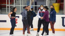 Varsity members of the figure skating team and their coaches at the University of Toronto standing on the ice at the rink.