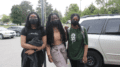 Three masked high school students pose for a photo in a parking lot.