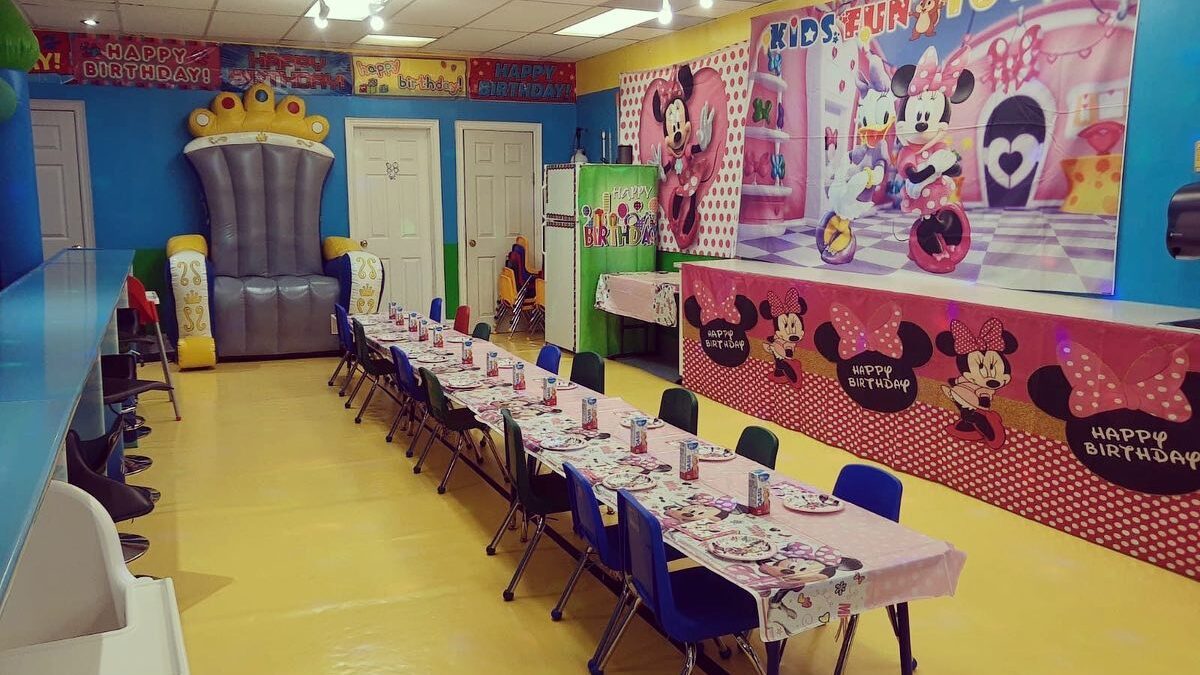 Minnie Mouse and princess themed birthday decorations are seen on the walls, table, and chairs of the party room at Kids Fun Town