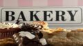 Baked goods such as cupcakes and butter tarts in front of a sign that reads 'BAKERY'.