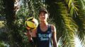 Kitana Lim of Eckerd College volleyball smiles under a palm tree with a ball.
