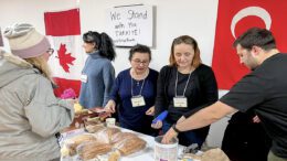 Volunteers putting money in a tin and helping a customer at the bake sale for Turkey earthquake relief