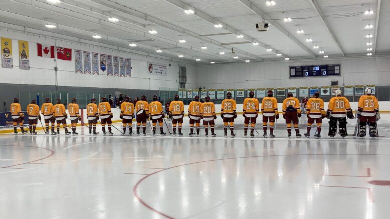 The Caledon Bombers hockey team line up on the ice pre-game wearing their yellow jerseys with burgundy pants.