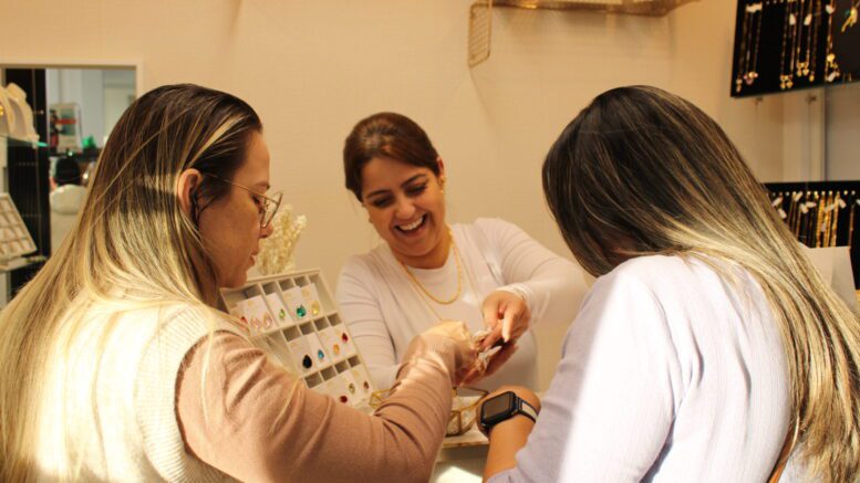 Mayara Hidalgo shows jewelry to two female customers.