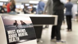 Male attendees stand a sign at the Movember Man's mental health event, which says: "Must knows about mental health."