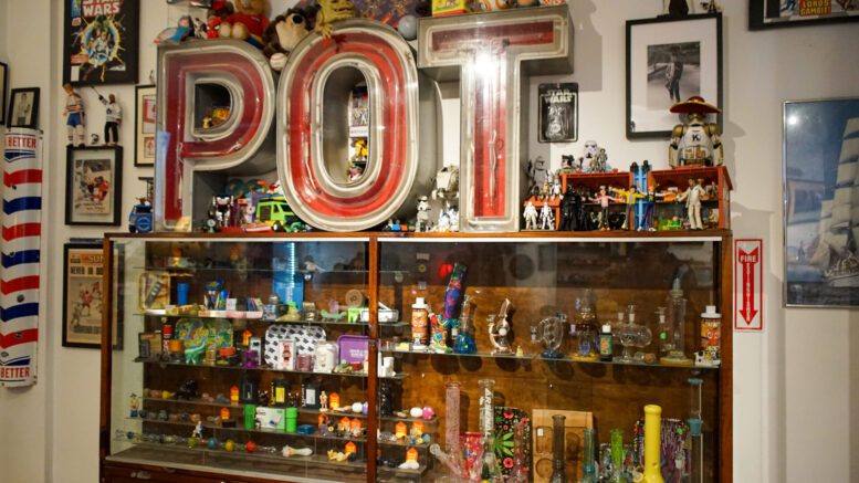 The word POT is displayed in big red letters on top of a shelf full of cannabis accessories.