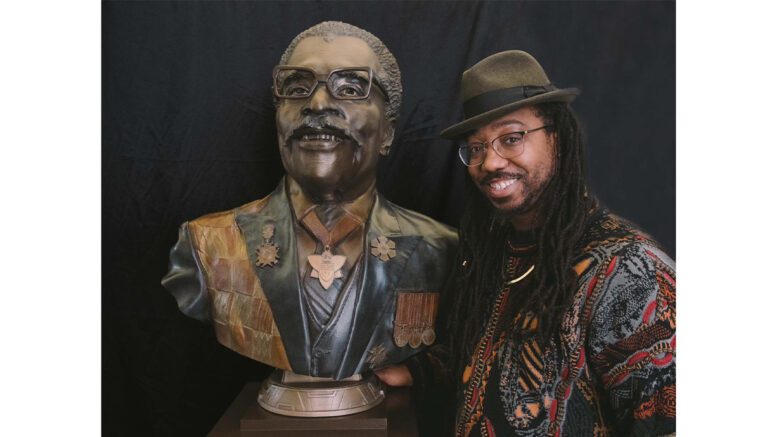 Quentin VerCetty, a visual storyteller based in North York, stands on the right side of the bust of Hon. Lincoln Alexander he sculpted.