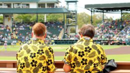 Two yellow shirts watching baseball.