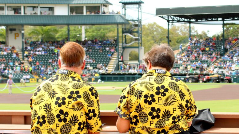 Two yellow shirts watching baseball.
