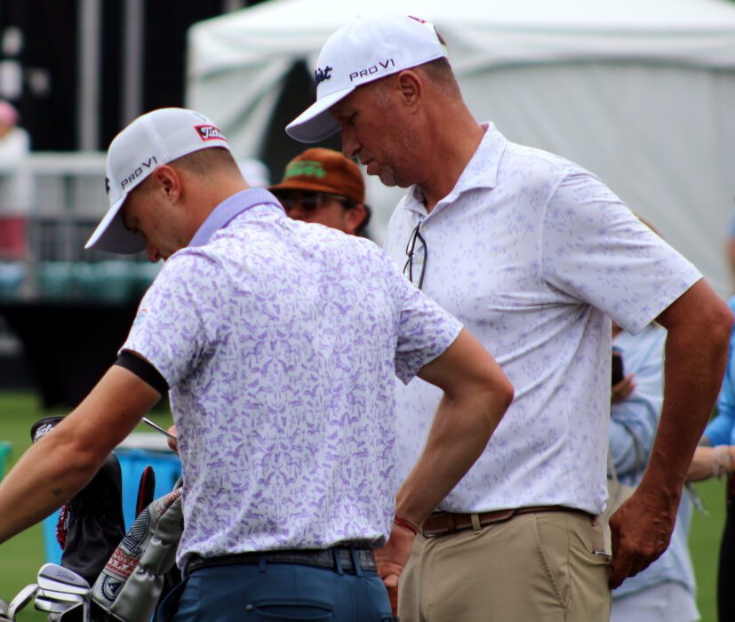 Justin and Mike Thomas look at their tablet after taking swings on the driving range during Tuesday's practice round. (Photo by: Justin Arenburg)