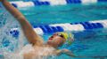 Swimmer on his back takes a deep breath mid breast stroke