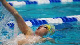 Swimmer on his back takes a deep breath mid breast stroke