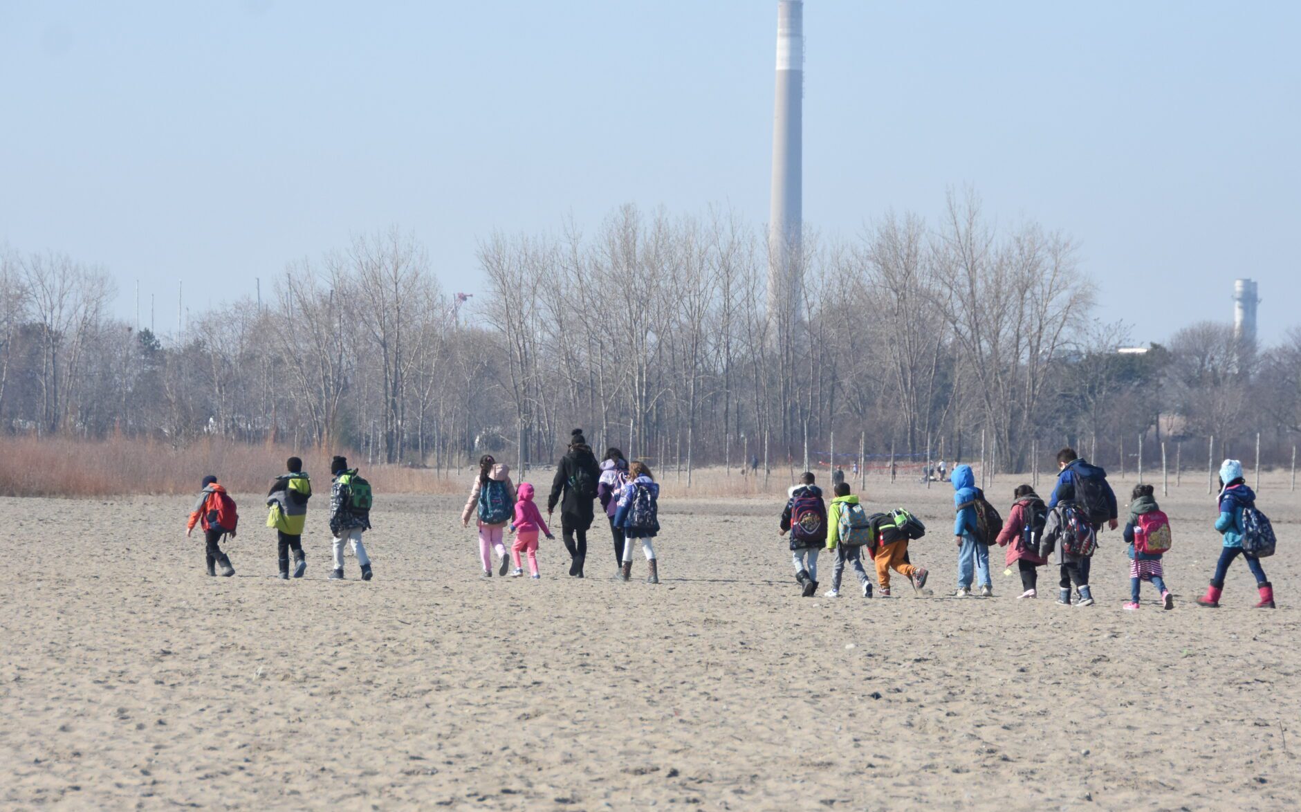 Kids walk in a single file along the beach