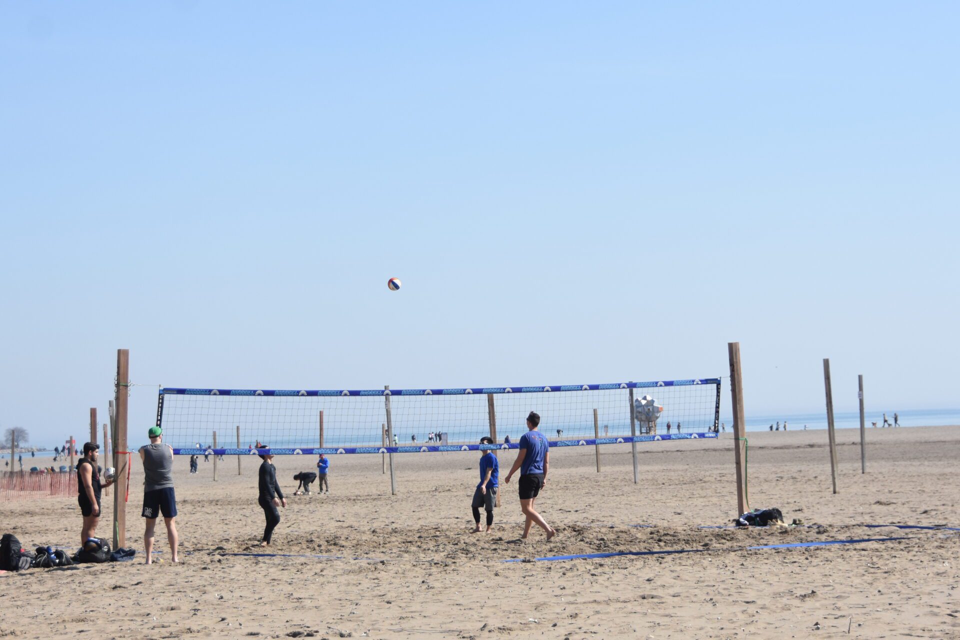 A group of boys playing volleyball as one of them prepares to hit the ball