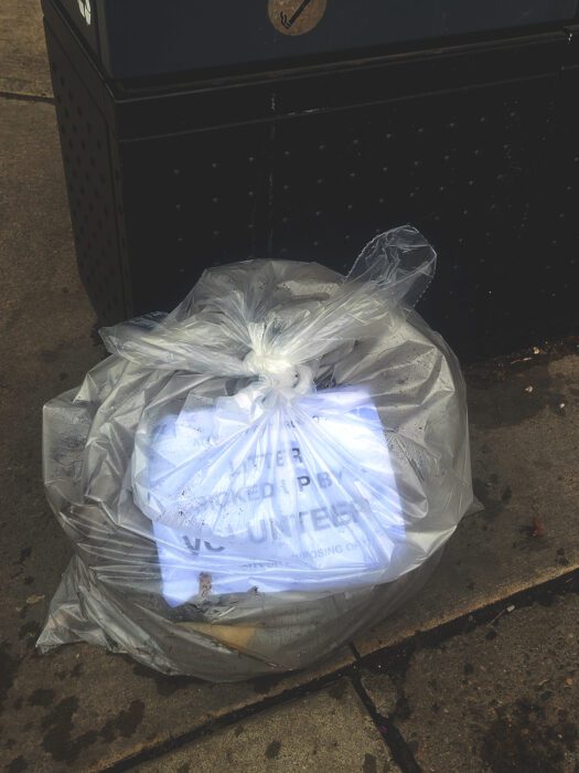 A bag filled with trash removed from the ground at Carlaw Avenue Parkette reads, "litter picked up by a volunteer," beside the garbage bin.