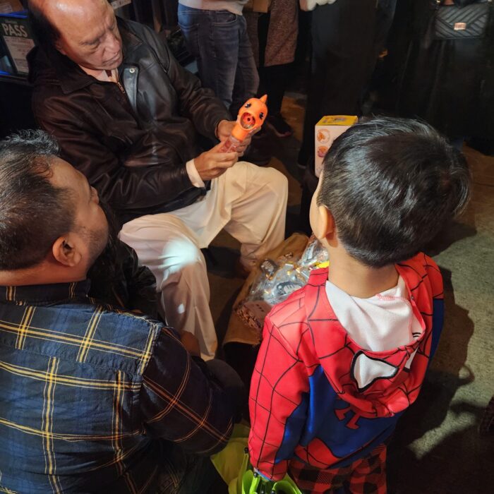 a father buys his son a toy from a street vendor on the eve of Eid on Gerrard Street