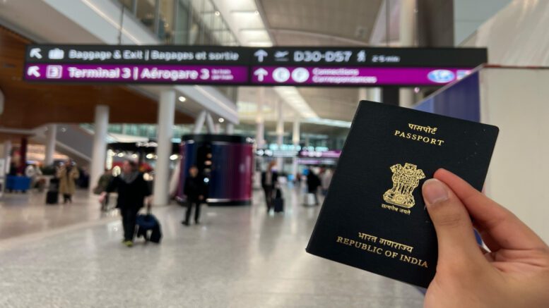 A person holds up a passport in an airport.