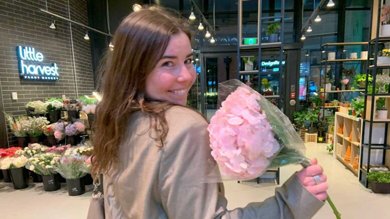 Sofie Katz looks over her right shoulder holding a bouquet of flowers